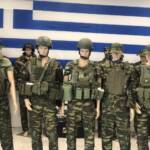 Μανεκέν με στρατιωτικές στολές μπροστά σε σημαία Ελλάδας.
