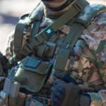 Στρατιωτική στολή με εξοπλισμό και ελληνική σημαία.