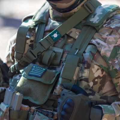 Στρατιωτική στολή με εξοπλισμό και ελληνική σημαία.