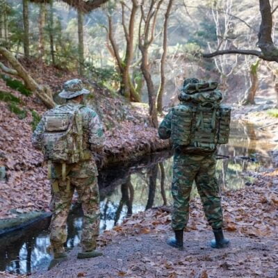 Στρατιωτικά πρόσωπα πεζοπορώντας δίπλα σε δάσος και ποτάμι.